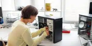 Seseorang merakit komputer server dengan membuka casing dan memasang kabel di meja kerja.