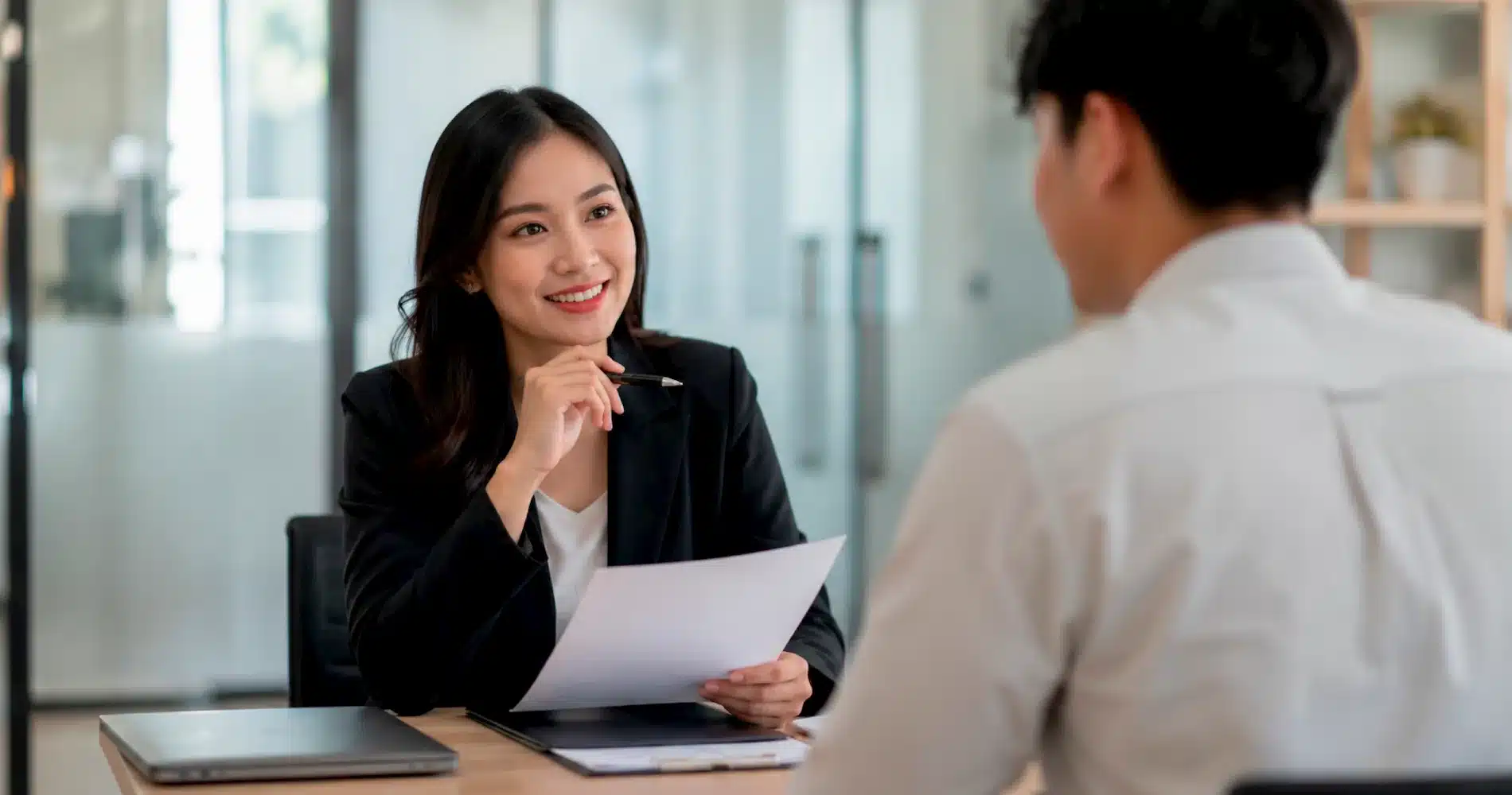 Beranda V2 21 Recruiter perempuan berbicara dengan kandidat pria sambil memegang dokumen saat wawancara kerja di kantor.